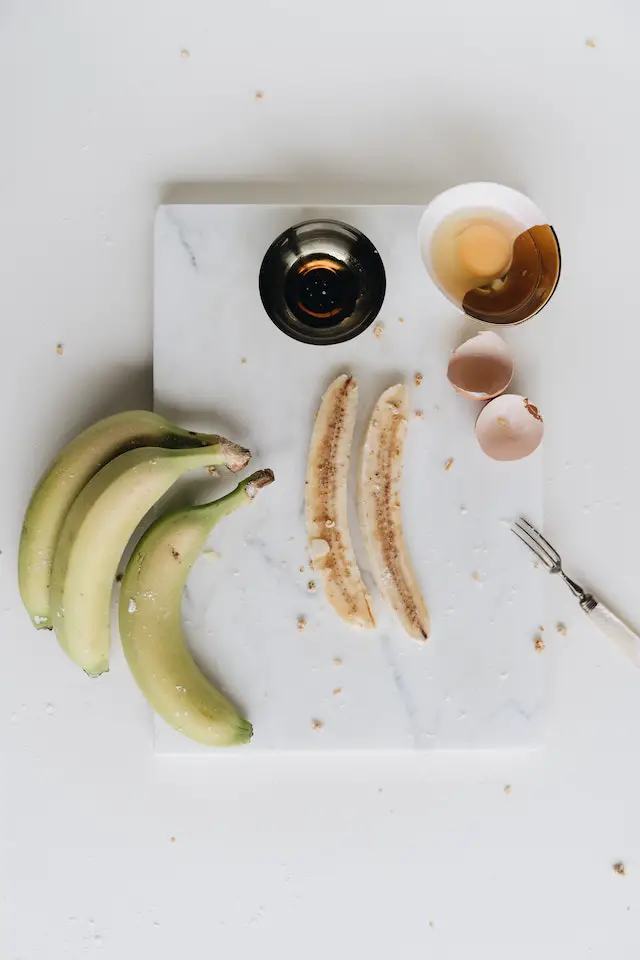 A flat-lay of a banana, egg shells, and two cups.