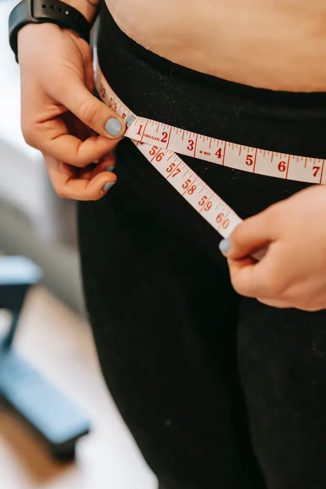 A woman measuring her waist for weight loss
