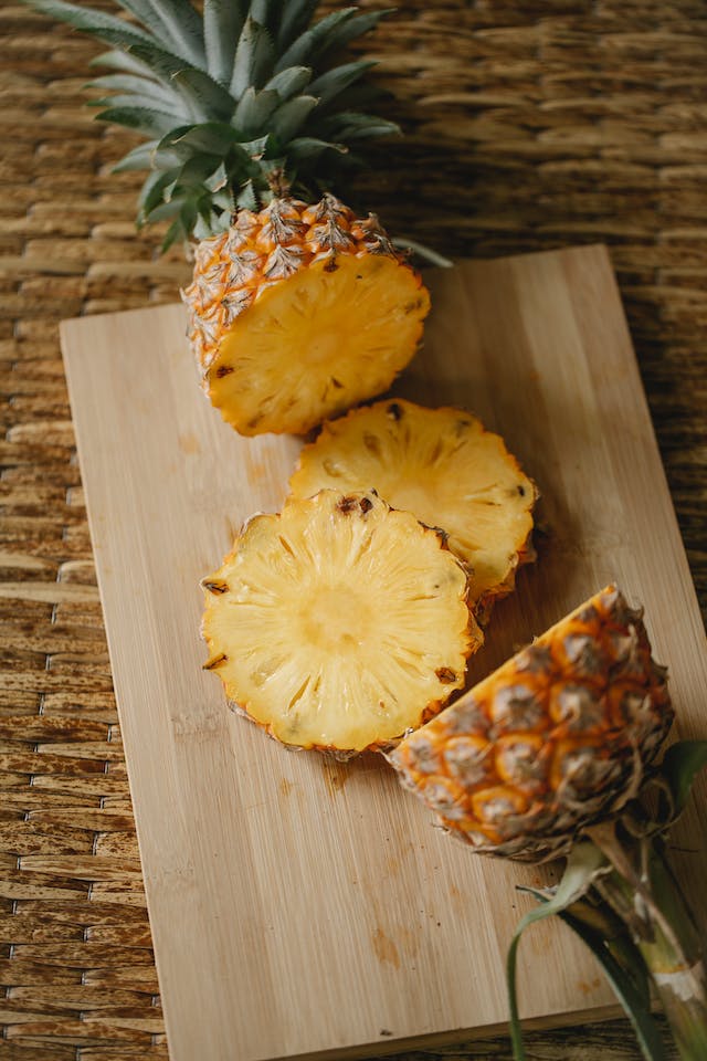 A sliced pineapple on a wooden chopping board.