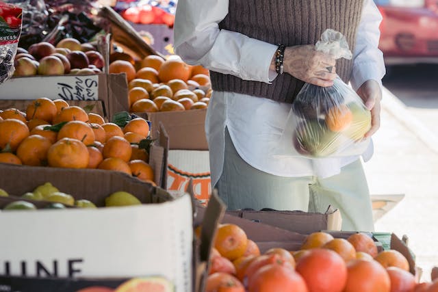 A woman buying citrus fruits from a fruit stand.