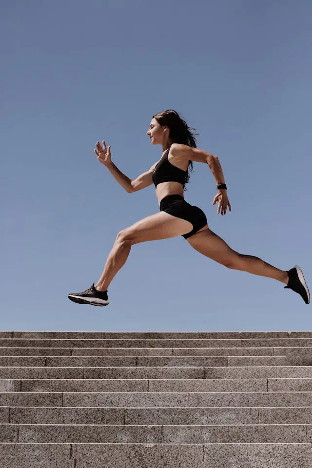 A woman in athletic wear running over the concrete stairs.